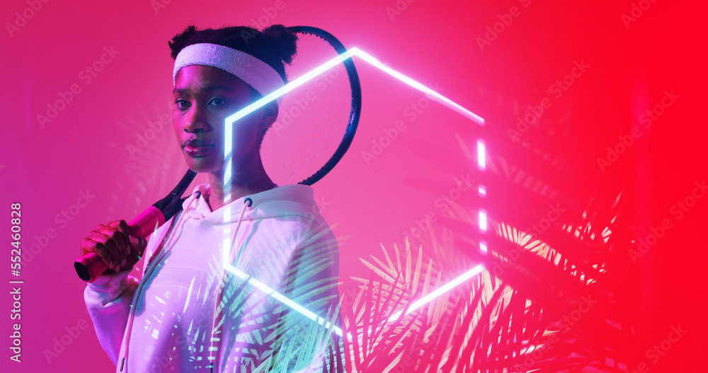 Biracial female player with racket standing by illuminated hexagon and plants on red background