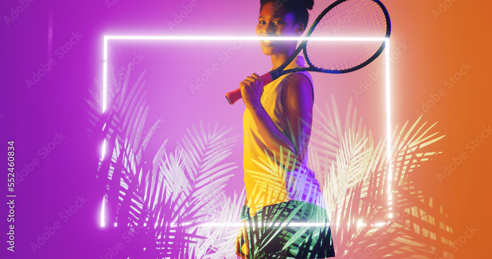 Side view of biracial female player with tennis racket standing by illuminated rectangle and plants