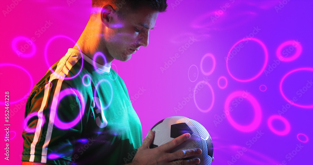 Composite of young caucasian player holding soccer ball with neon pattern in background, copy space