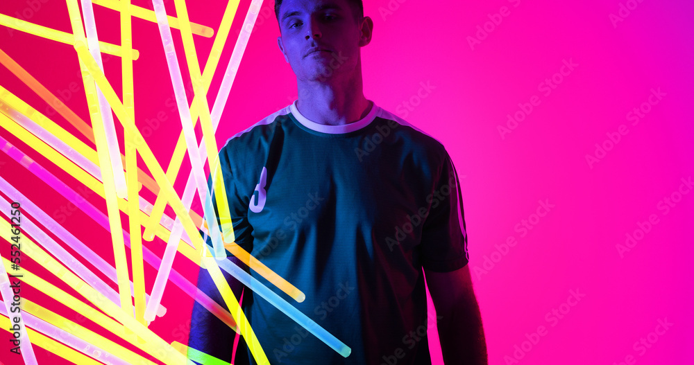 Portrait of caucasian young sportsman with colorful neon design over pink background, copy space