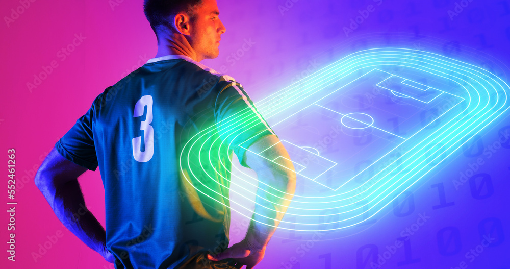 Confident caucasian player with arms akimbo by neon soccer field over blue and pink background