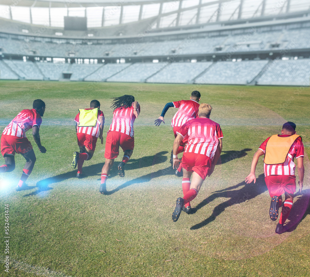 Rear view of multiracial male soccer players in sports clothing running in stadium