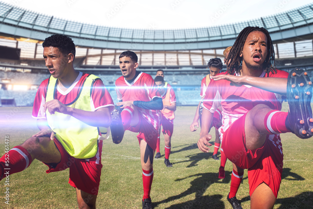 Determined team of multiracial male soccer players in sports clothing exercising in stadium