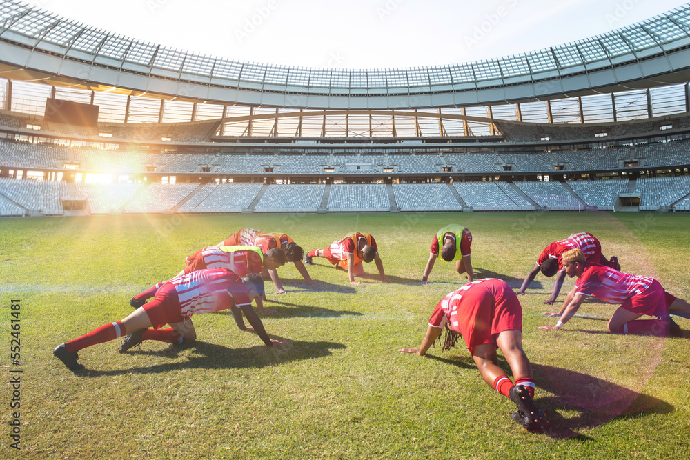 Team of multiracial male players in sports clothing exercising in soccer field