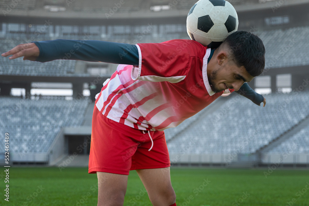 Biracial young soccer player balancing ball on back while practicing in stadium, copy space