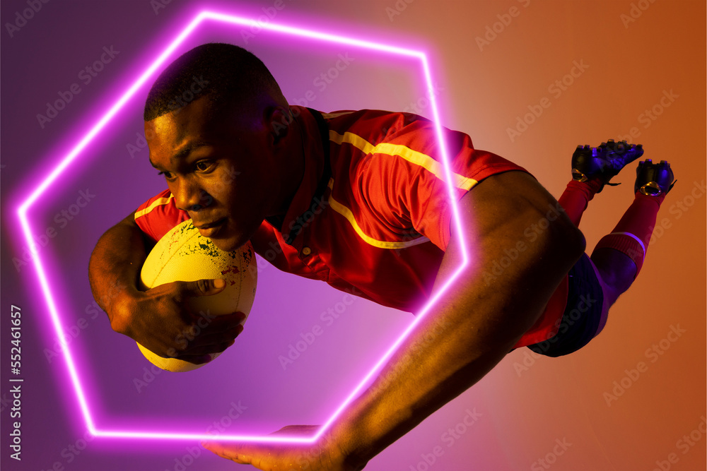 Hexagon neon over african american young rugby player jumping against colored background