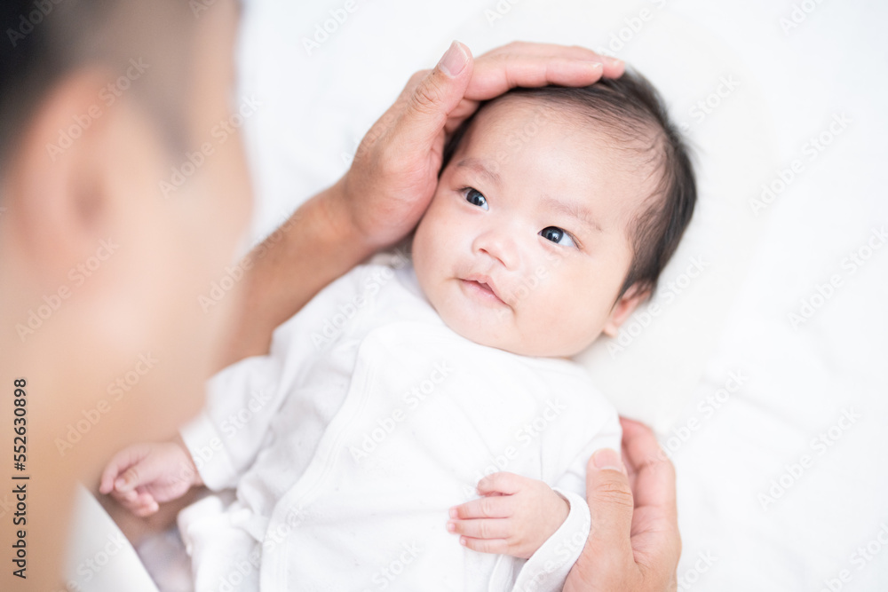 パパに手を添えられて幸せそうな生後2か月の赤ちゃん