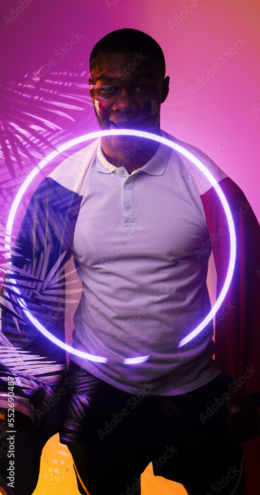 Portrait of smiling african american rugby player with illuminated circle and plants