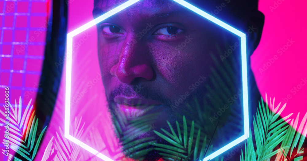 Close-up of african american male player with tennis racket by illuminated hexagon and plants