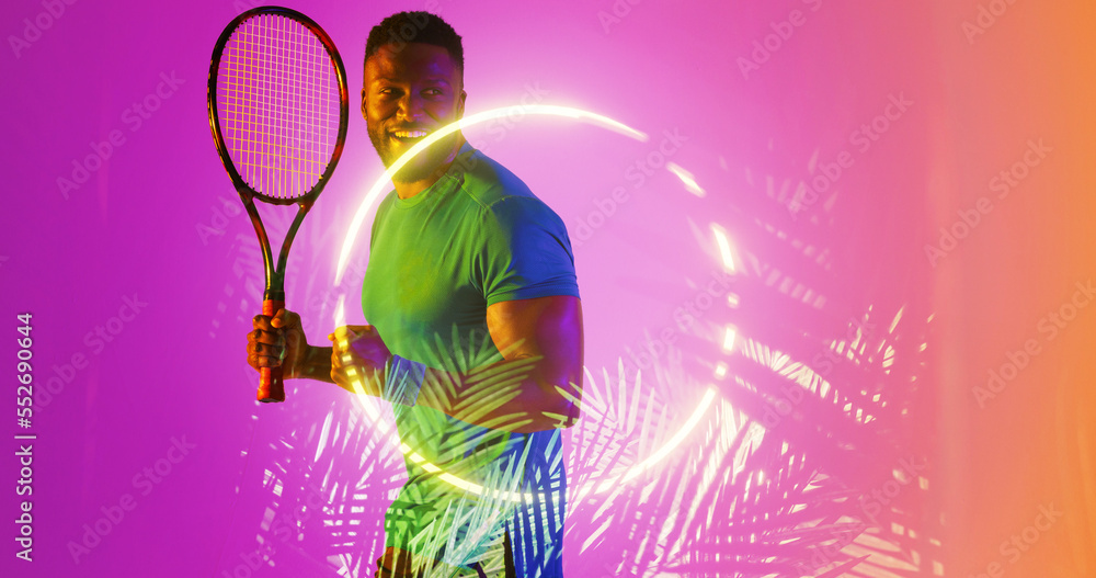 Happy african american tennis player holding racket by illuminated plants and circle