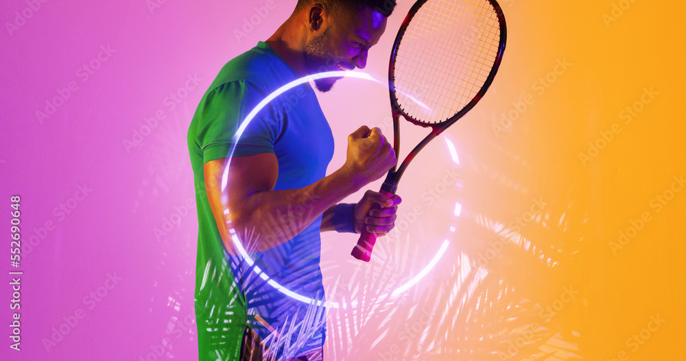 Side view of african american male player with racket shaking arms by illuminated plants and circle