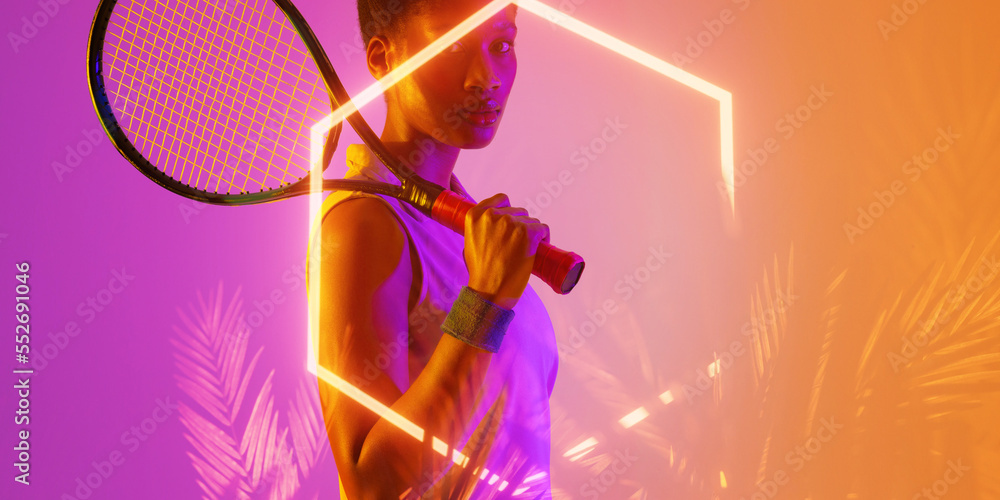 Confident african american female tennis player sholding racket by illuminated hexagon and plants