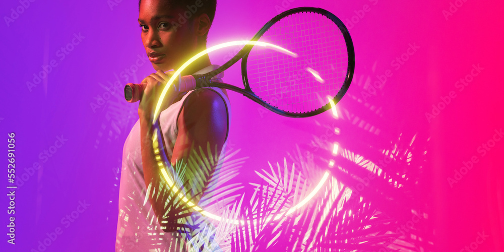 Side view of african american female tennis player with racket by illuminated circle and plants