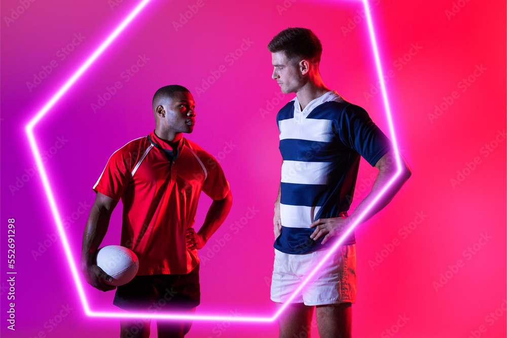 Multiracial male rugby opponents looking at each other by illuminated hexagon on pink background