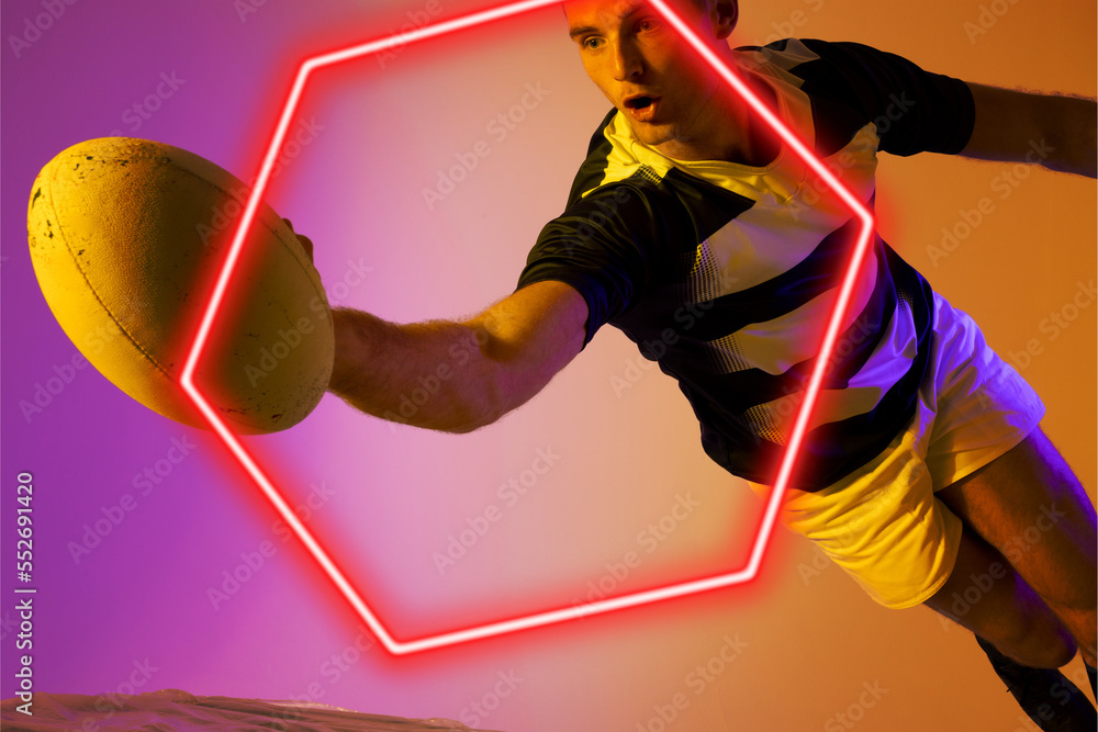 Caucasian male rugby player with ball jumping by illuminated hexagon on gradient background