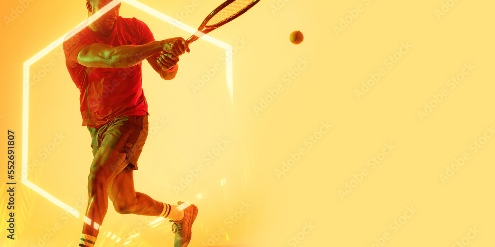 Illuminated hexagon over midsection of african american male tennis player hitting ball with racket