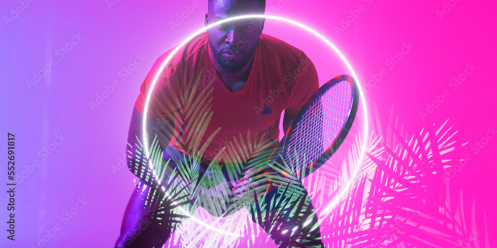 Illuminated circle and plants over african american male player holding racket on colored background