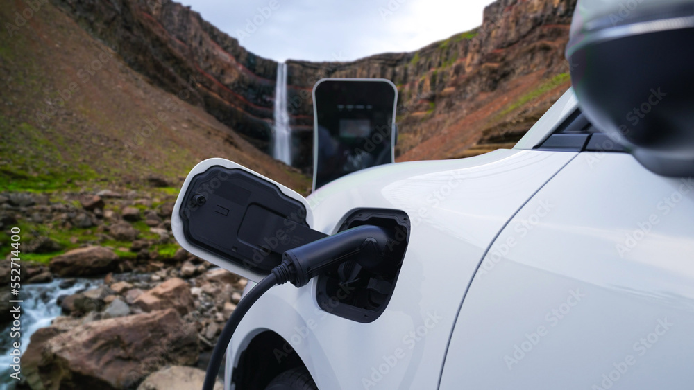 Electric car charging energy from charging station in the natural scenery, waterfall and stream back