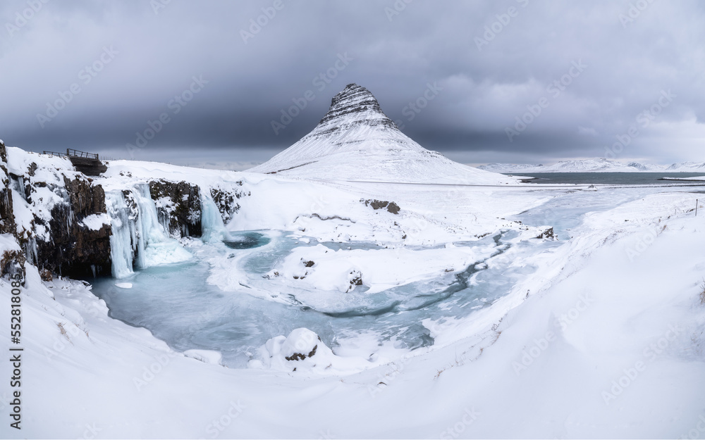 Kirkjufell mountain, Iceland. Winter landscape. The mountain and the waterfall. Snow and ice. A popu