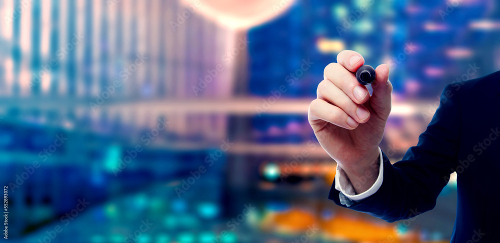 Businessman holding a marker on night city background