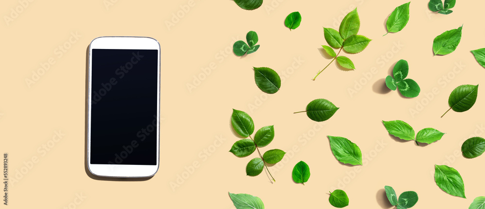 White smartphone with green leaves - flat lay