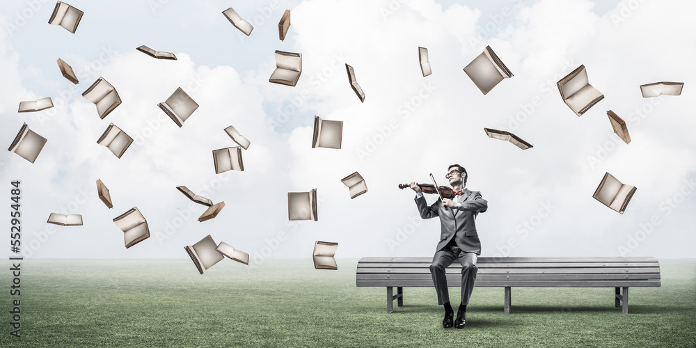 Handsome businessman in park on wooden bench play his melody