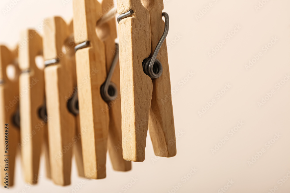 Wooden clothespins hanging on rope against color background, closeup