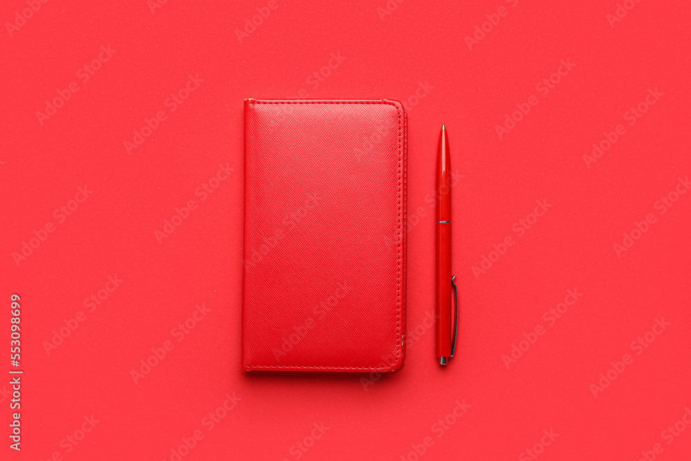 Notebook and pen on red background