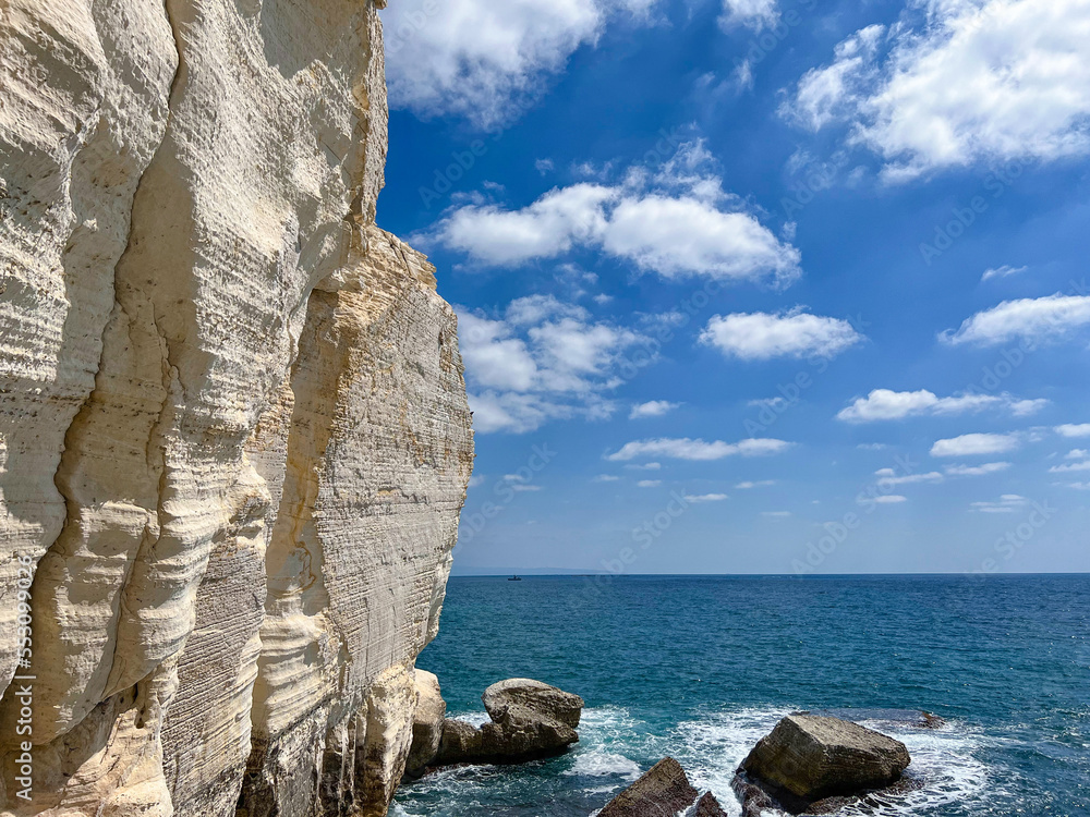 View of high cliff and sea water on sunny day