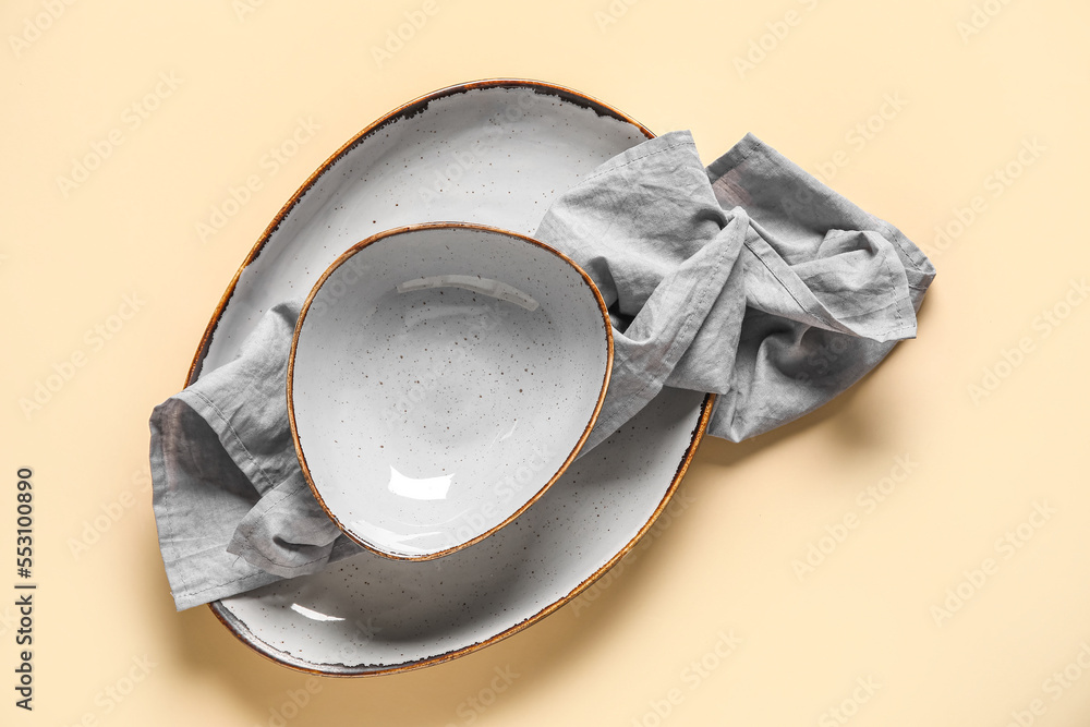 Plate with bowl and napkin on beige background