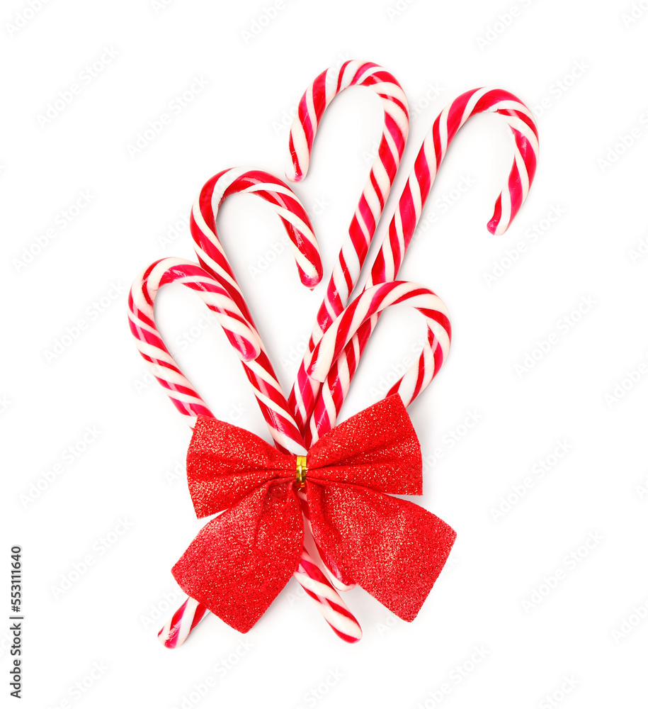 Sweet candy canes with Christmas bow on white background