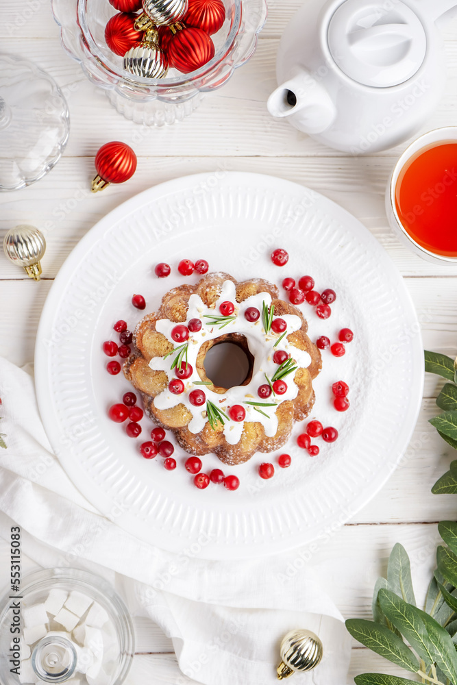 Plate of tasty Christmas cake, cup of tea and decorations on light wooden background