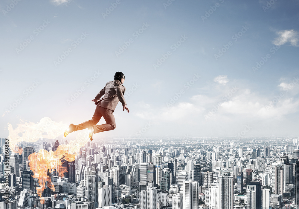 Businessman in suit and aviator hat flying in sky