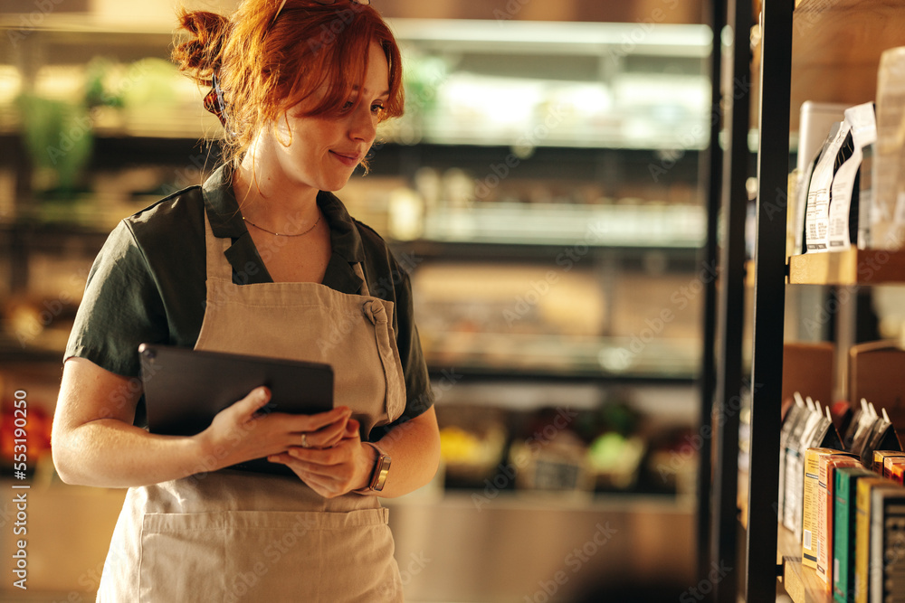 Cheerful shop owner stocktaking in her grocery store