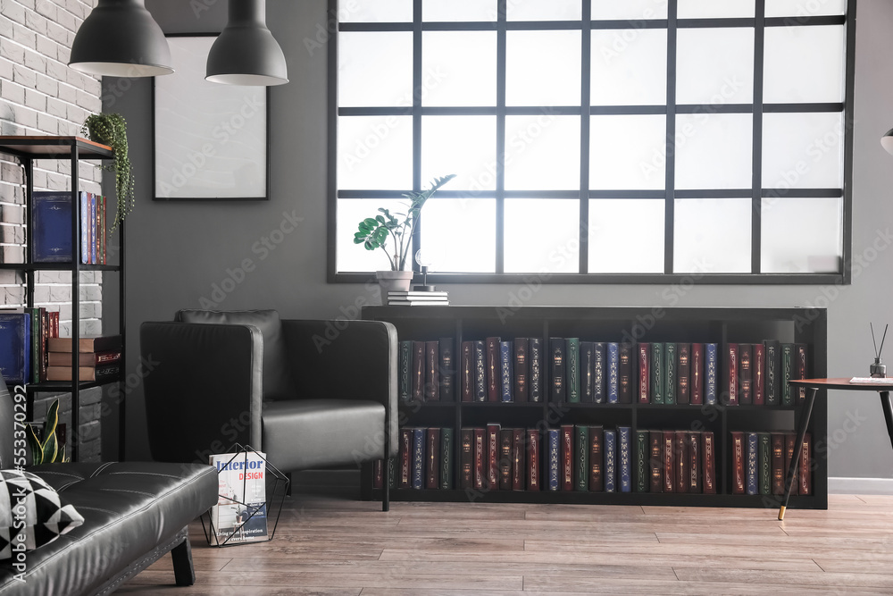 Bookshelves, armchair and sofa in stylish library interior