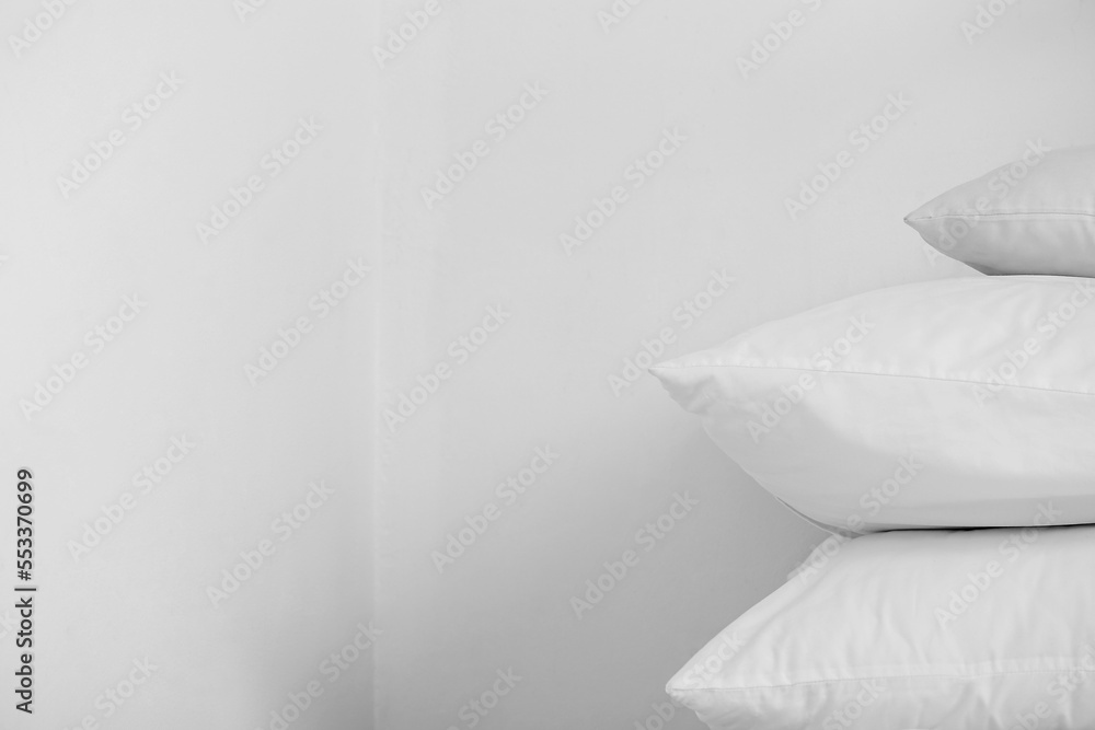 Stack of white pillows near light wall