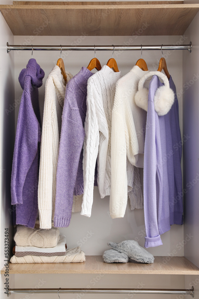 Warm sweaters and sleepers on shelf in wardrobe