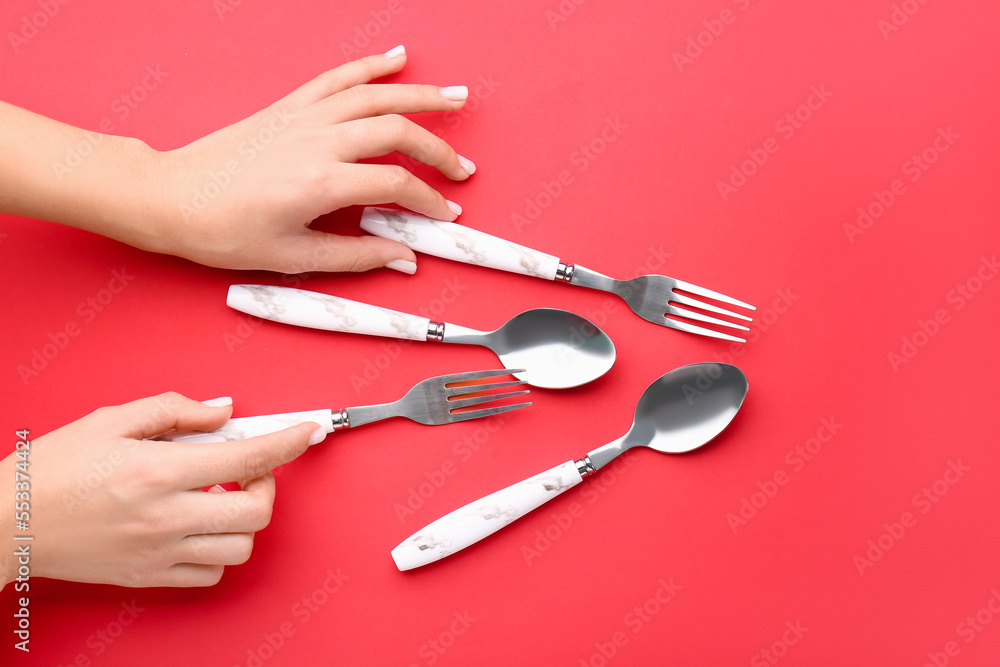 Woman with silver cutlery on red background