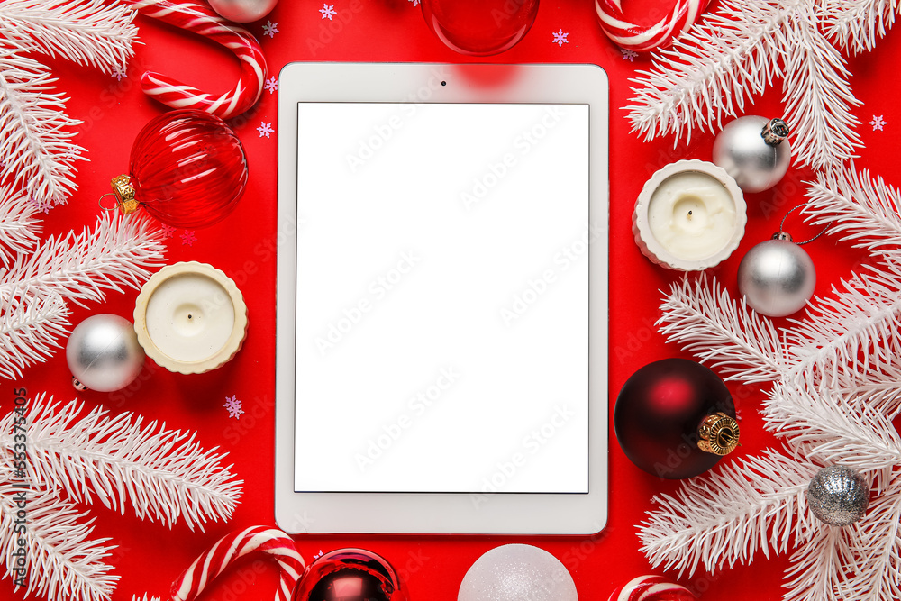 Blank tablet computer with Christmas decor on red background