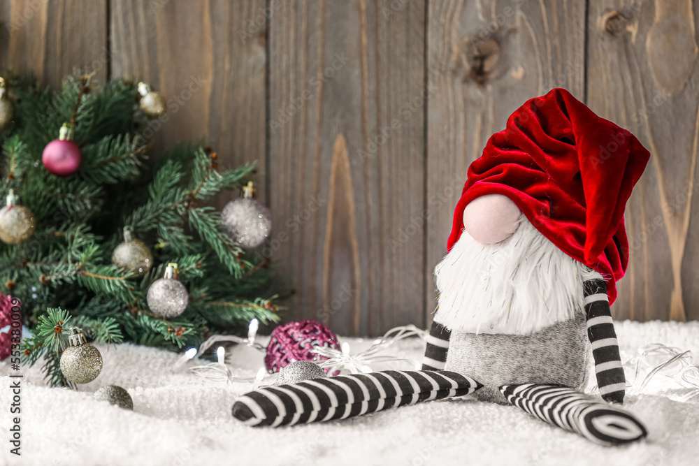 Christmas gnome and decorations on light fabric against wooden background