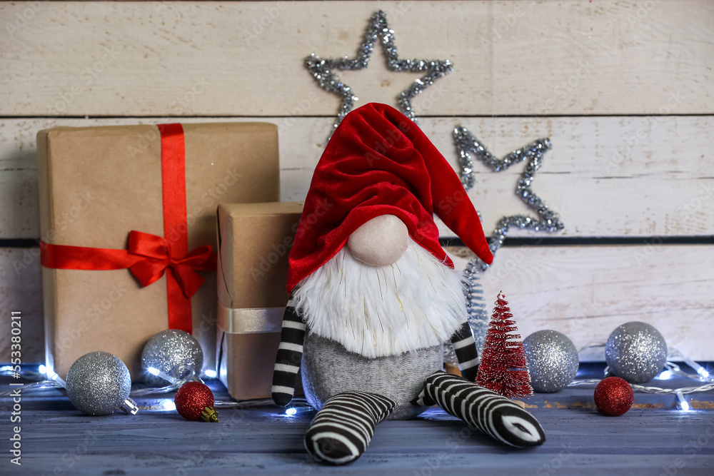 Composition with Christmas gnome, gift boxes and decorations on wooden table