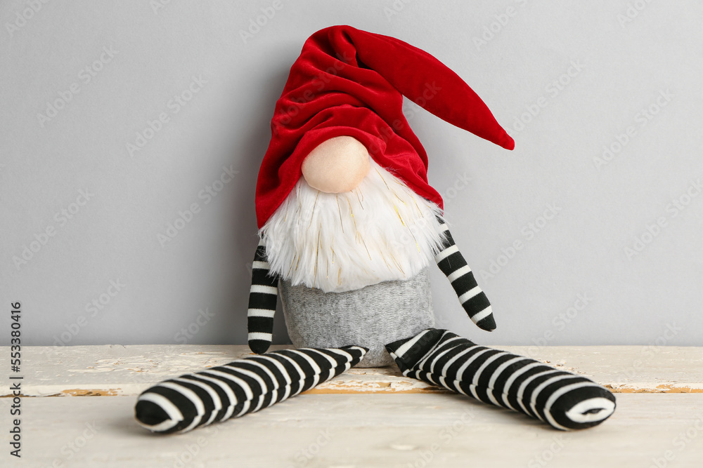 Christmas gnome on light wooden table against grey background