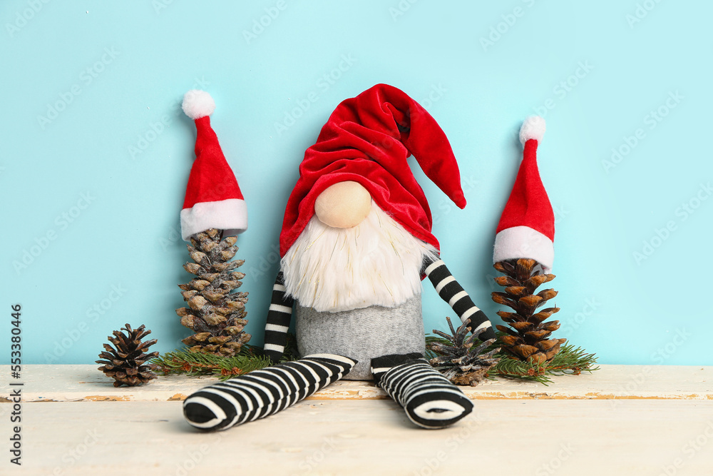 Christmas gnome, fir branches and cones on light wooden background on color background