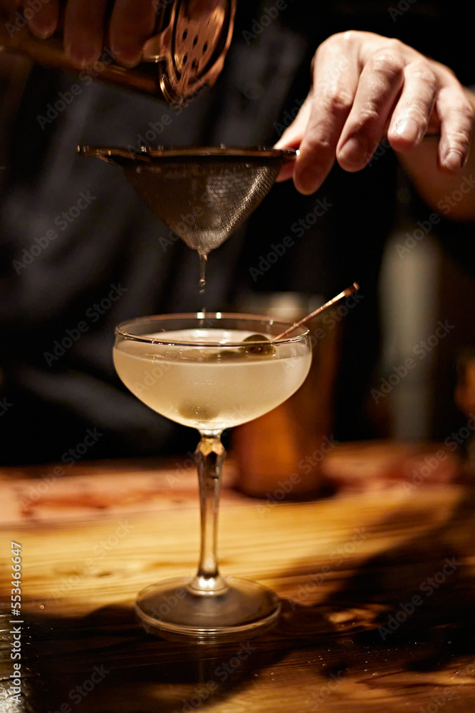 Barman making a martini cocktail at a bar