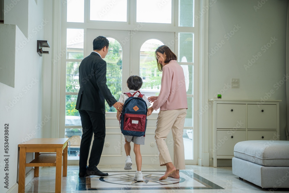 家长帮助儿子穿制服准备离家上学。