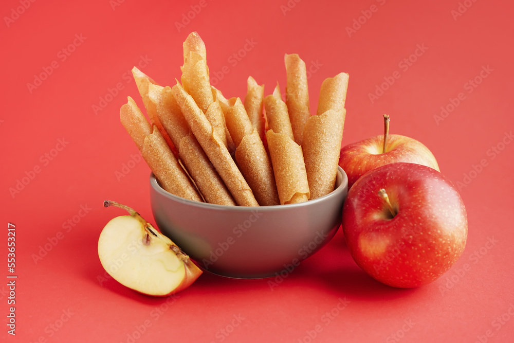 Bowl of tasty apple pastilles on red background