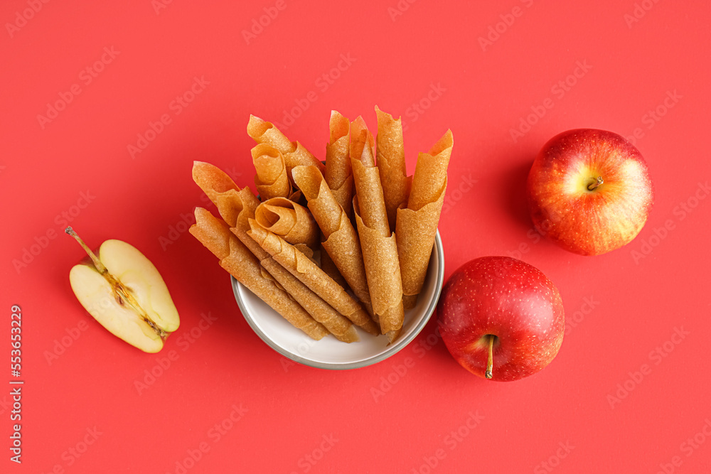 Bowl of tasty apple pastilles on red background