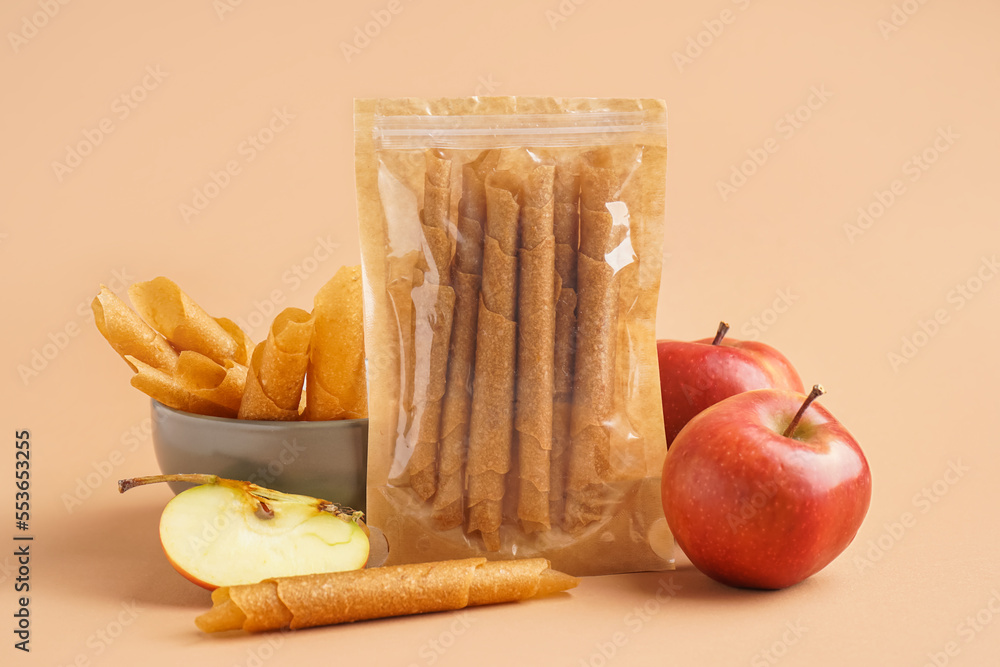 Bag with tasty apple pastilles on color background