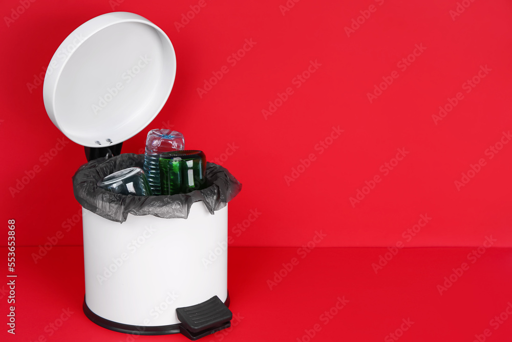 Open rubbish bin with trash on red background