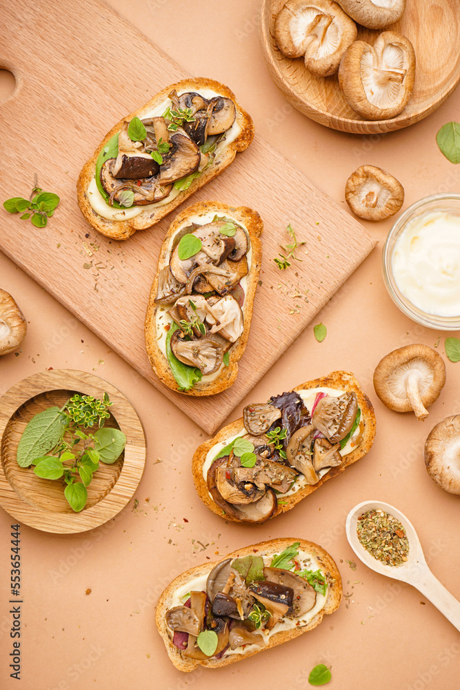 Tasty toasts with mushrooms and bowl of sauce on beige background